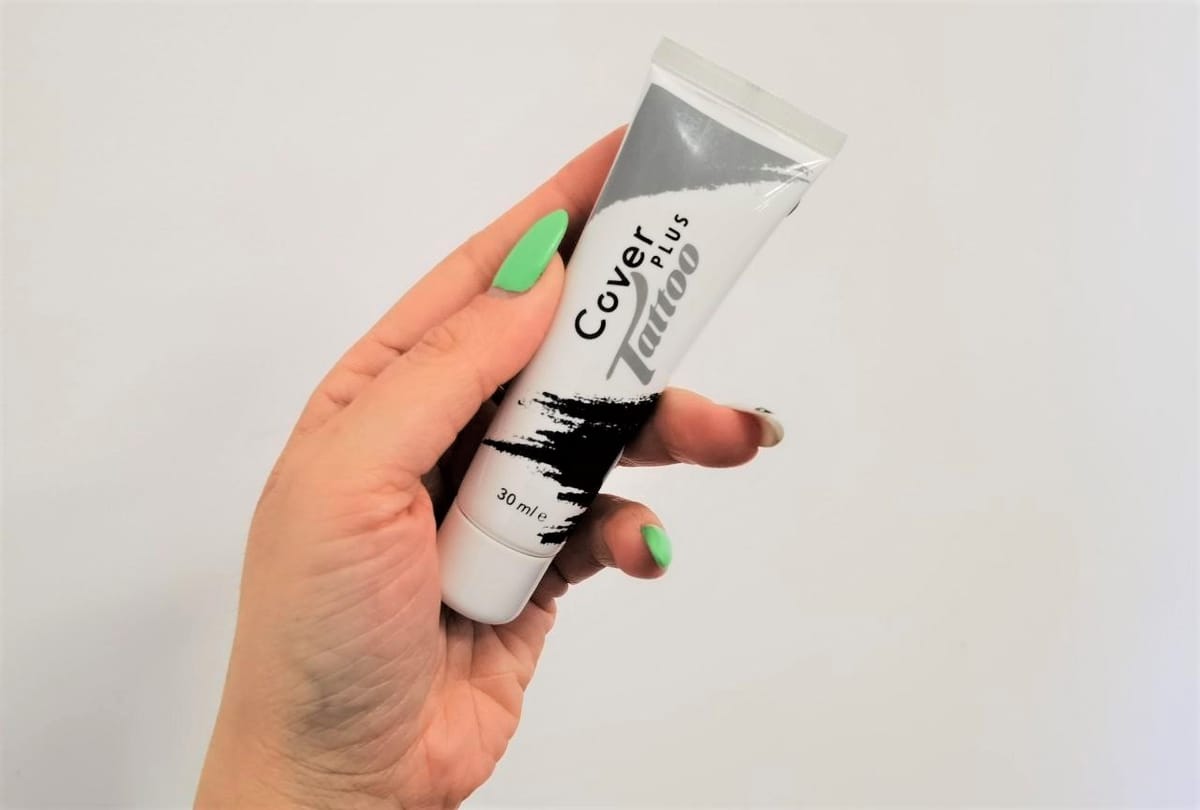 Il tubetto della crema coprente impugnato in verticale, pronto per l’applicazione