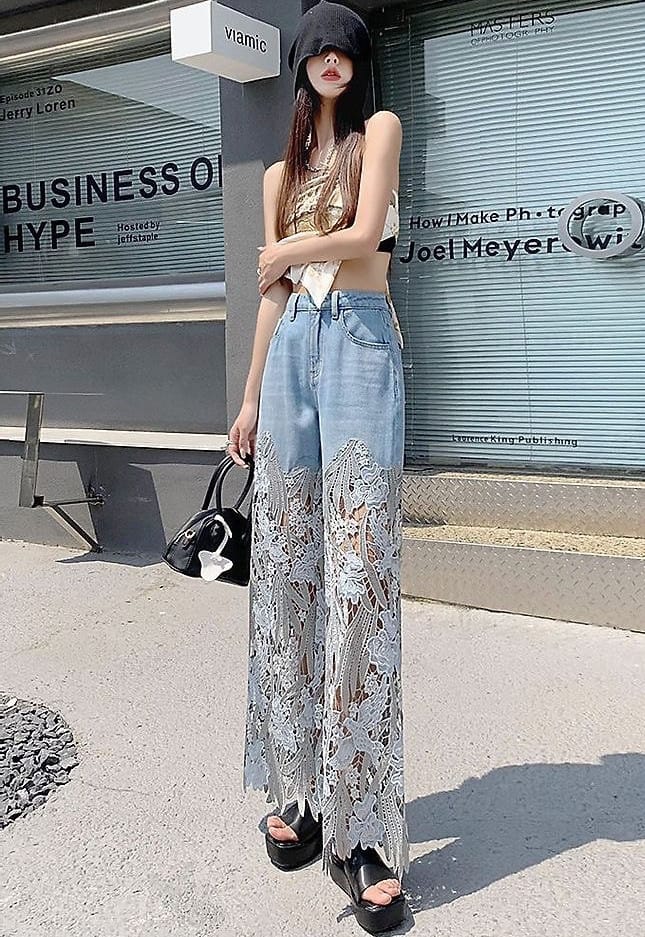 Ragazza in strada con jeans chiari a gamba larga e pizzo floreale dal ginocchio all’orlo, top dorato