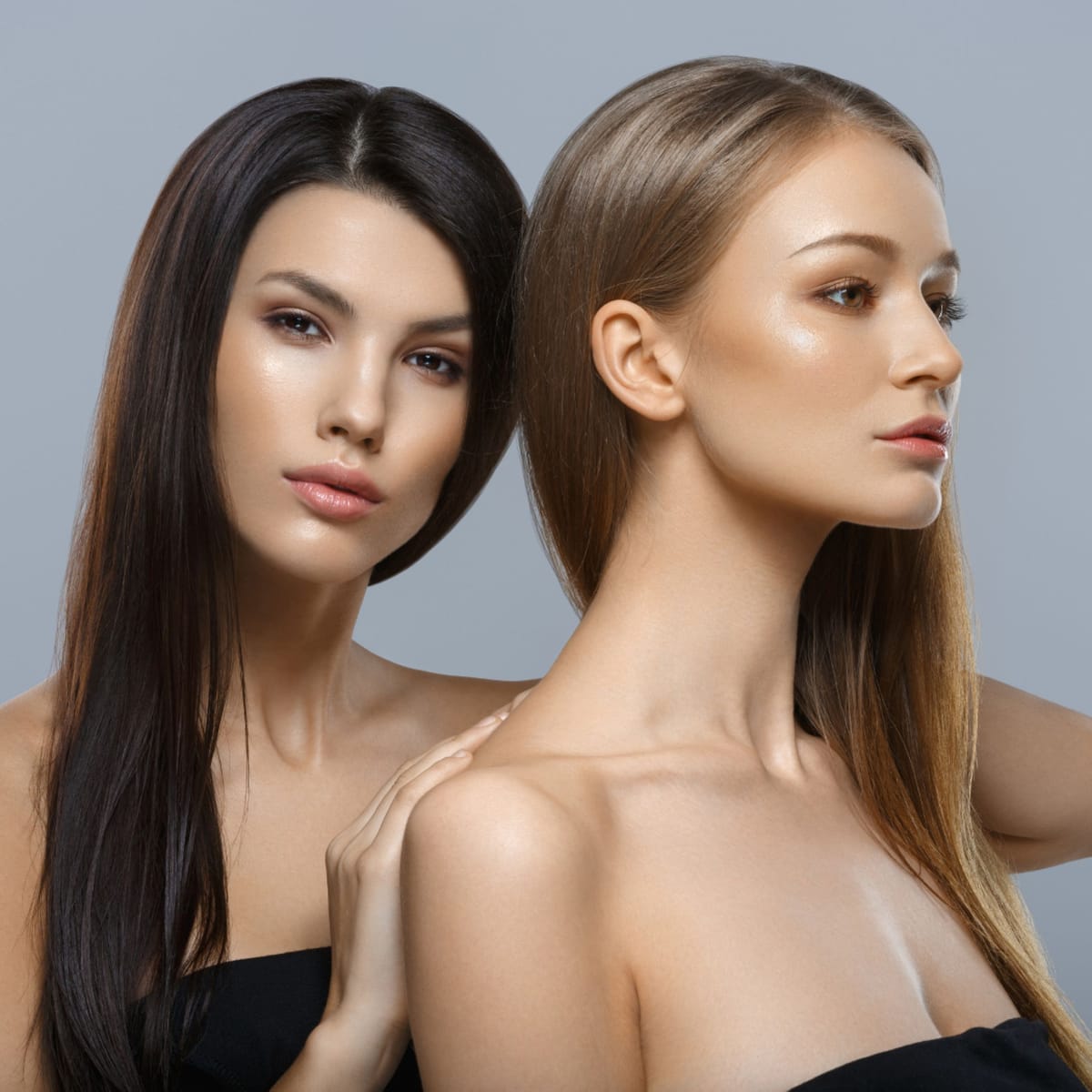 Due modelle affiancate con lunghi capelli lisci, castano scuro e biondo, su fondo grigio
