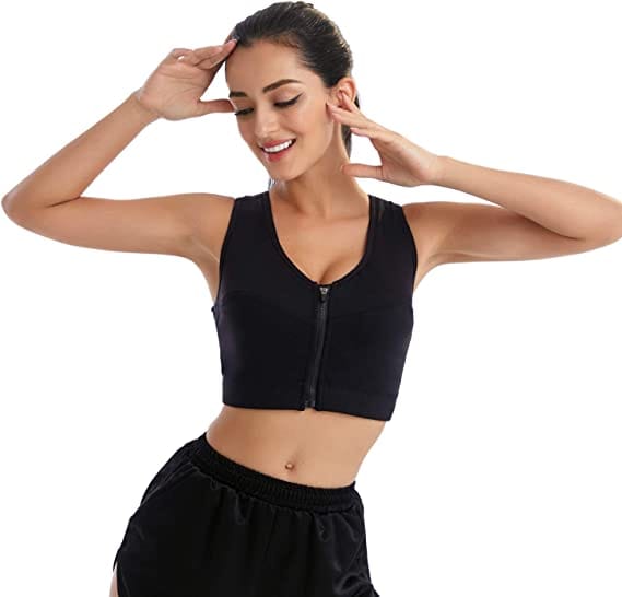 Donna sorridente con le mani tra i capelli indossa il reggiseno sportivo nero e pantaloni da ginnastica