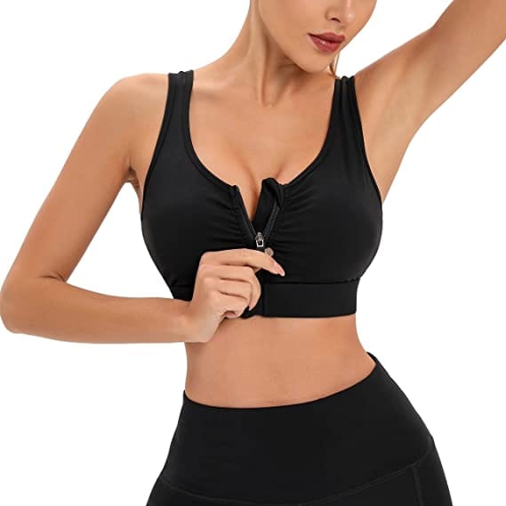 Mano che apre la zip frontale del reggiseno sportivo nero, indossato con leggings scuri
