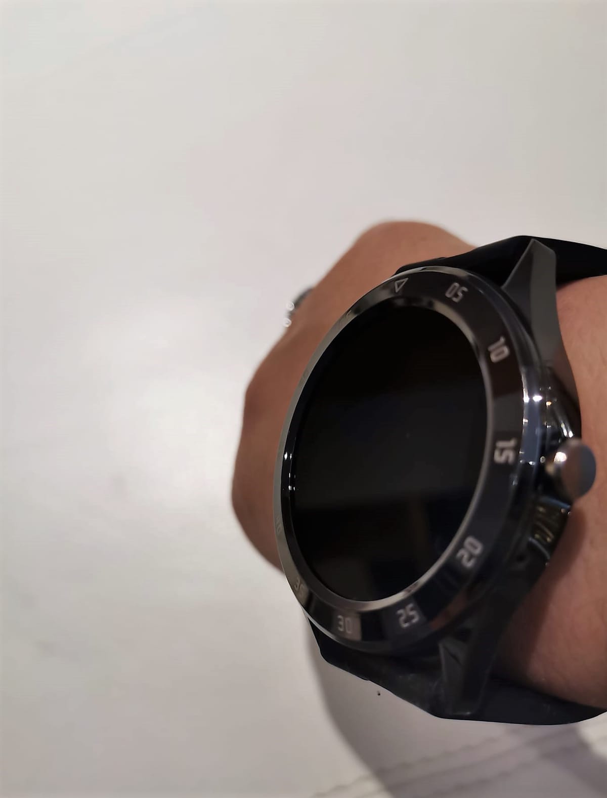 Smartwatch nero indossato al polso, ripreso da vicino con la ghiera numerata e il display spento