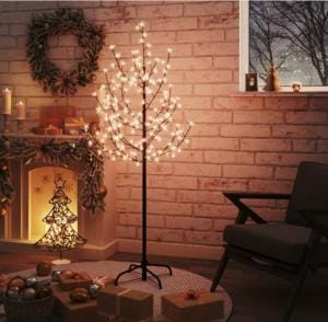 Albero a LED acceso in un salotto decorato per Natale, con luce calda che si riflette sul muro di mattoni