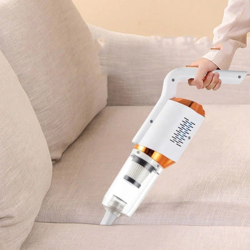 Aspirabriciole bianco e arancio impugnato a mano mentre aspira la seduta di un divano beige