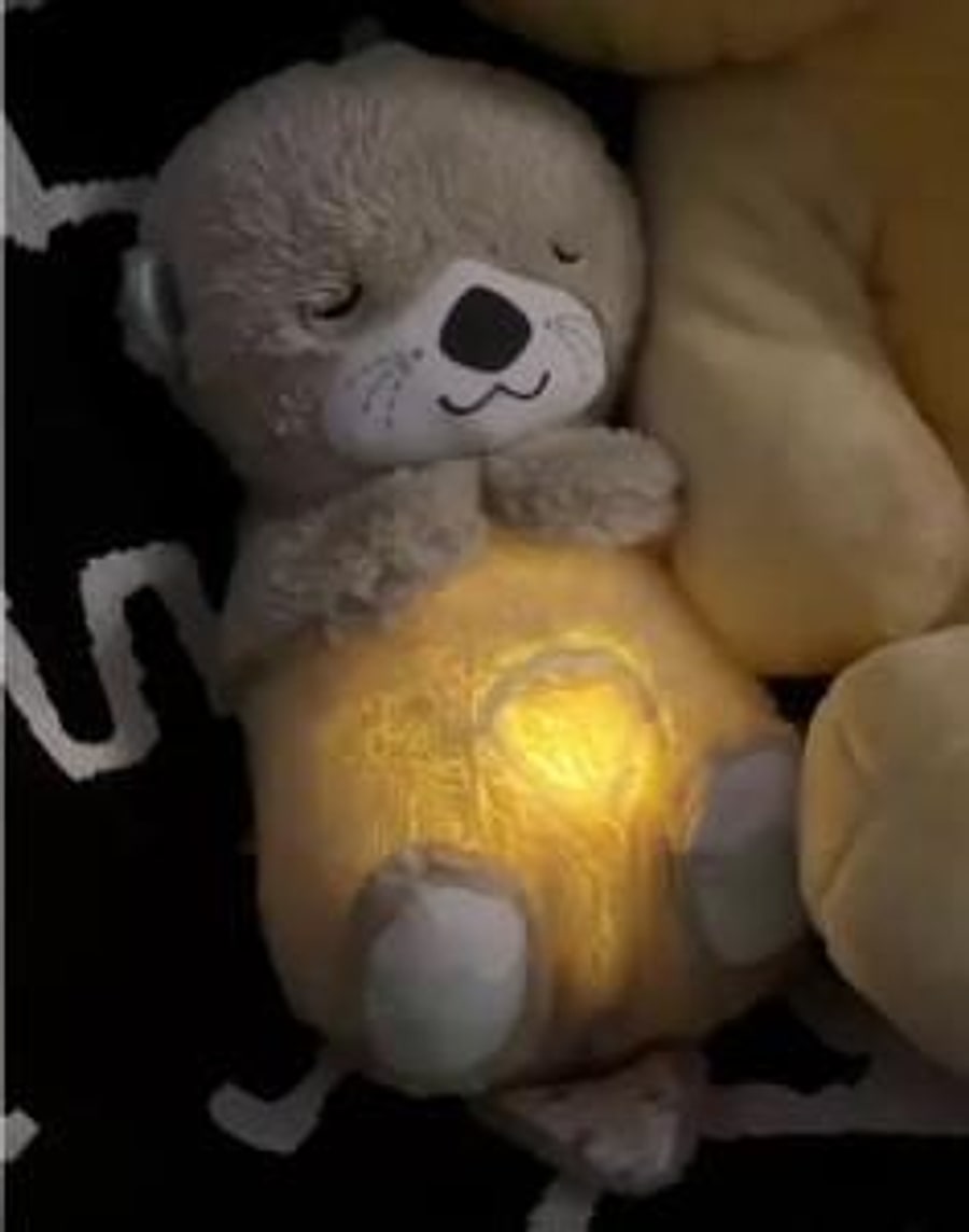 Il peluche luminoso appoggiato sul letto al buio, con la luce soffusa che pulsa lentamente sulla pancia