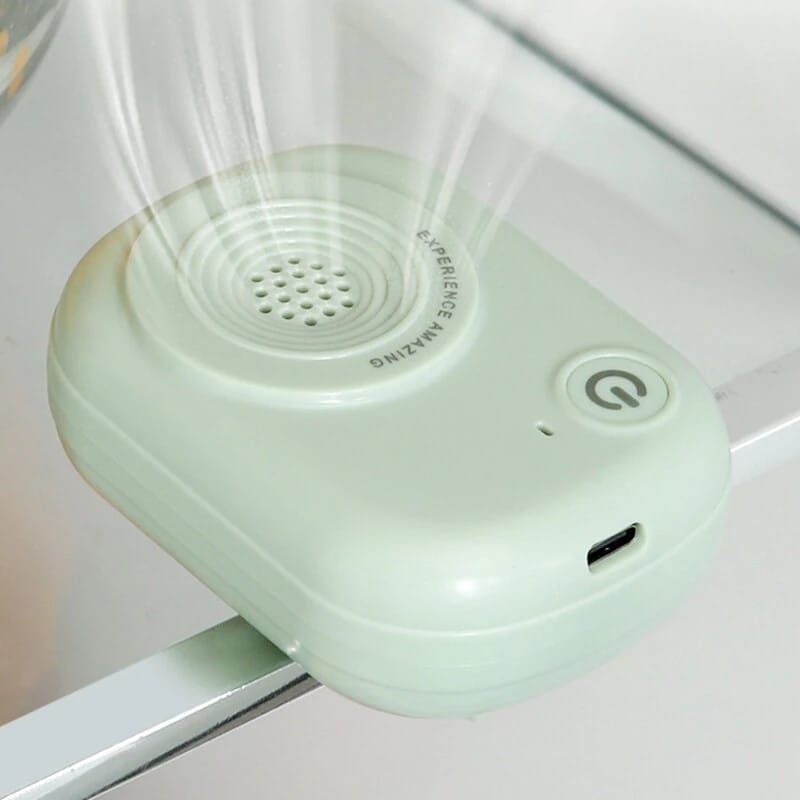 Purificatore verde menta agganciato al ripiano in vetro del frigorifero, con il flusso d'aria in evidenza