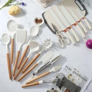 Utensili in silicone bianco con manici in legno su un piano di marmo, accanto ai coltelli e alle forbici